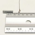 Clasp (with a steel spring) of a 10 kt white gold chain lying on a flat surface, 15 mm from a strong rare earth magnet – just beginning to get attracted to the magnet