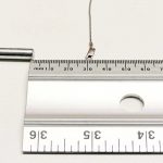 Clasp (with a steel spring) of a 10 kt white gold chain lying on a flat surface, 30 mm from a strong rare earth magnet – not attracted to the magnet