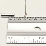Clasp (with a steel spring) of a 10 kt white gold chain lying on a flat surface, 20 mm from a strong rare earth magnet – not attracted to the magnet