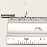 Clasp (with a steel spring) of a 10 kt white gold chain lying on a flat surface, 20 mm from a strong rare earth magnet – not attracted to the magnet