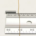 Fake gold chain (gold plated on a steel base) lying on a flat surface, 8 mm from a strong rare earth magnet – beginning to get attracted to the magnet